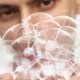 En person håller en klunga av vita pormaskar, som ser ut som små, runda bubblor.