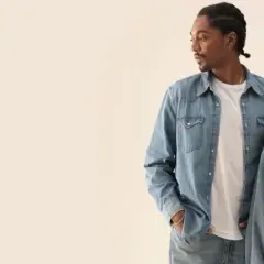 Två personer i jeanskläder, en man med flätor och en kvinna med blont hår, i en levis reklam.
