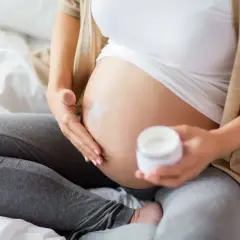 Gravid kvinna smörjer magen med kräm. Niacinamid kan vara bra för huden under graviditeten.