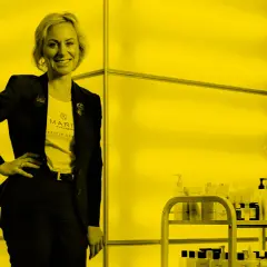 Maria Åkerberg, med en t-shirt med hennes namn, står stolt bredvid en hylla med hudvårdsprodukter.