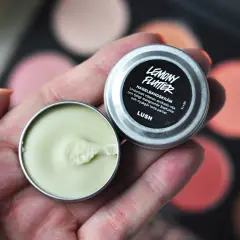 En hand håller en burk med Lemony Flutter nagelbands-kräm, perfekt för torra nagelband.