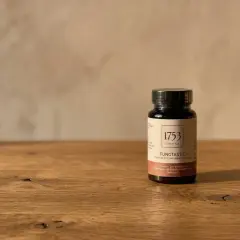 En mörk flaska med "1753 LIFESTYLE FUNGTASTIC" och text om kollagen hudvård.