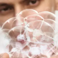 En person håller en klunga av vita pormaskar, som ser ut som små, runda bubblor.