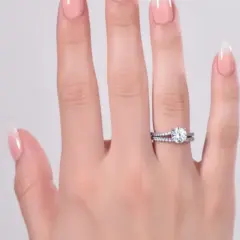 En hand med perfekt manikyr hemma visar upp en gnistrande diamantring och en matchande vigselring.