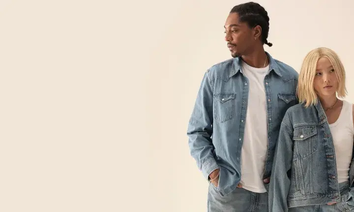 Två personer i jeanskläder, en man med flätor och en kvinna med blont hår, i en levis reklam.