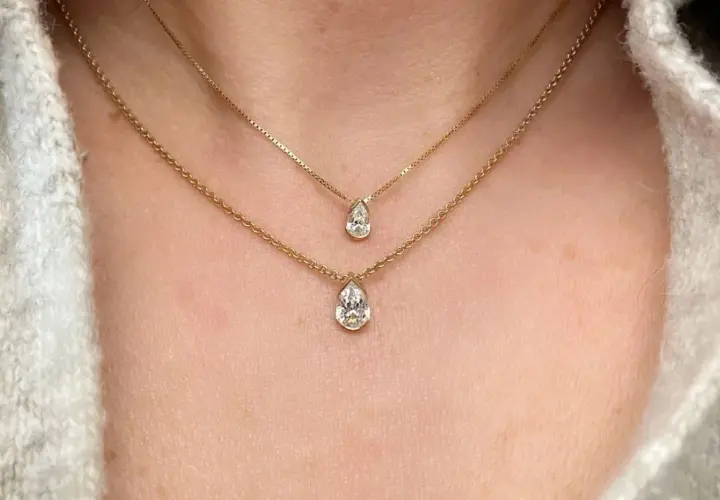 Två guldhalsband med päronformade diamanter, ett elegant val av moderna smycken som framhäver halsens linjer.