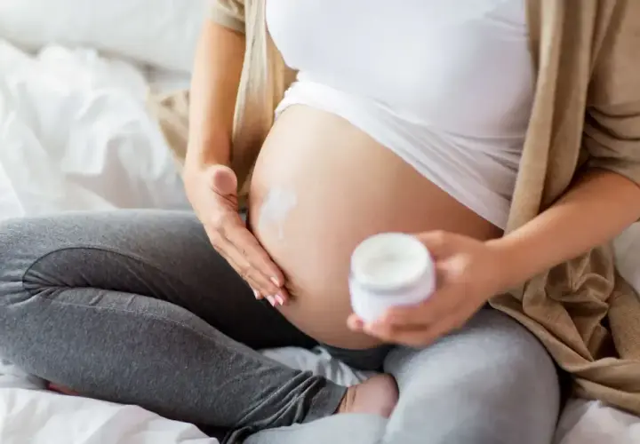 Gravid kvinna smörjer magen med kräm. Niacinamid kan vara bra för huden under graviditeten.
