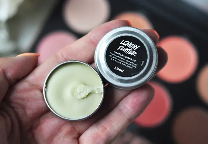 En hand håller en burk med Lemony Flutter nagelbands-kräm, perfekt för torra nagelband.