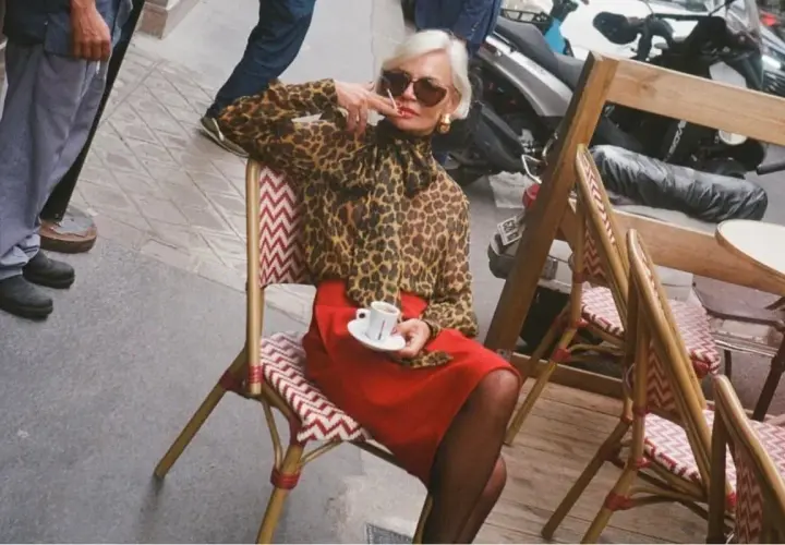 Elegant dam i leopardmönstrad blus och röd kjol, en kaffe i handen. En stil som inspirerar för vårmode 2026 dam.