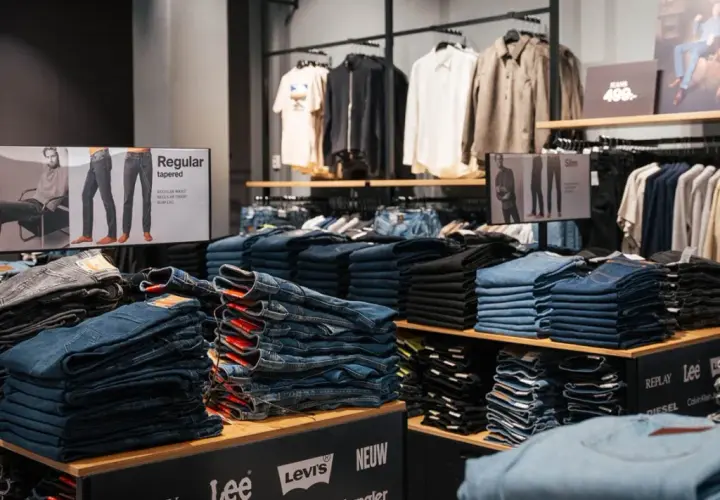 Staplade jeans i olika tvättar och modeller, inklusive "regular tapered" och "slim". En skylt visar olika passformer.