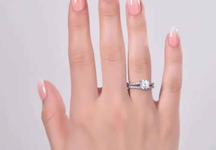 En hand med perfekt manikyr hemma visar upp en gnistrande diamantring och en matchande vigselring.