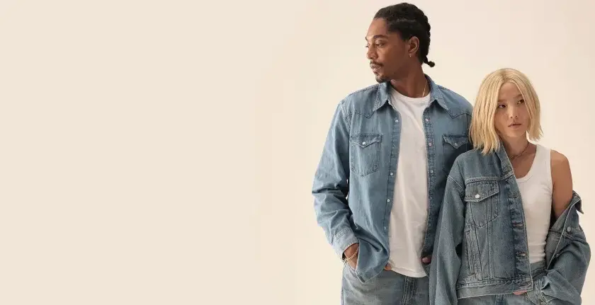 Två personer i jeanskläder, en man med flätor och en kvinna med blont hår, i en levis reklam.