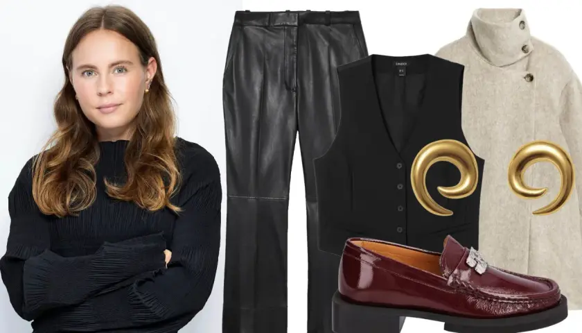 Woman in black top next to VILA leather pants, black vest, beige coat, burgundy loafers, and gold earrings.