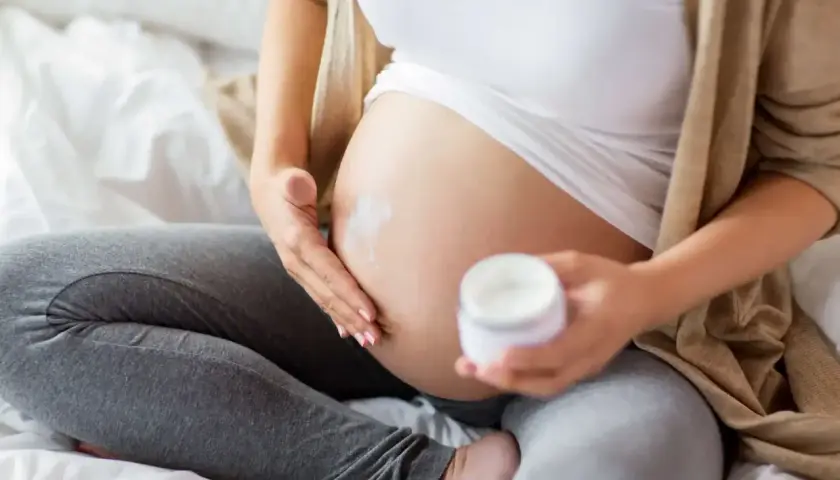 Gravid kvinna smörjer magen med kräm. Niacinamid kan vara bra för huden under graviditeten.