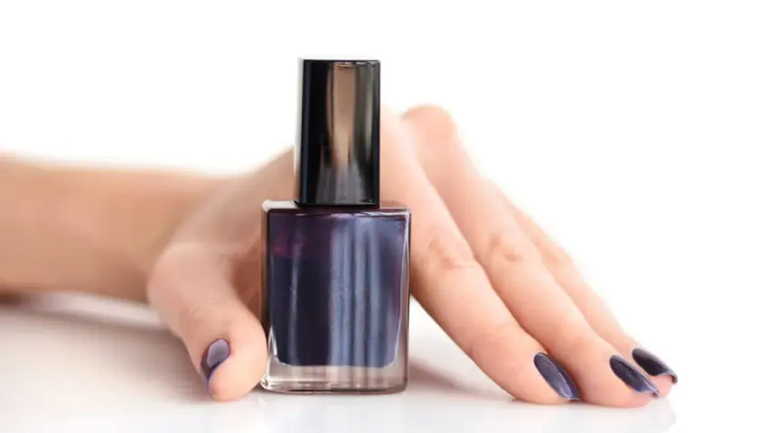 Mörkblått nagellack i en flaska, med en hand som visar matchande naglar. Perfekt för att torka nagellack snabbt.