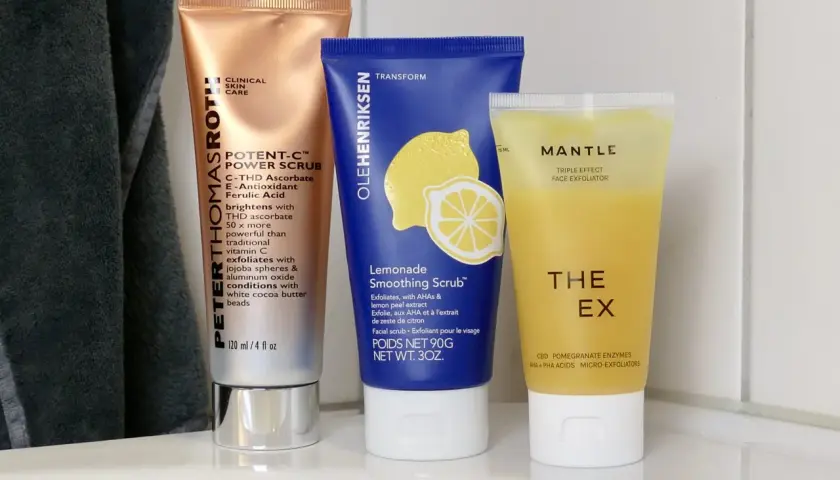Tre tuber med ansiktsskrubb: en kopparfärgad, en blå med citron och en gul. Dessa produkter erbjuder mekanisk peeling för huden.