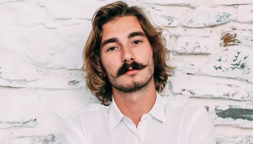 Ung man med långt hår och en imponerande mustasch som visar upp olika mustasch stilar.