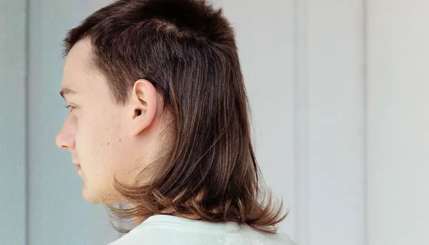 Profilbild på en person med en modern mullet. Håret är mörkbrunt och stylat med kortare topp och längre nacke.