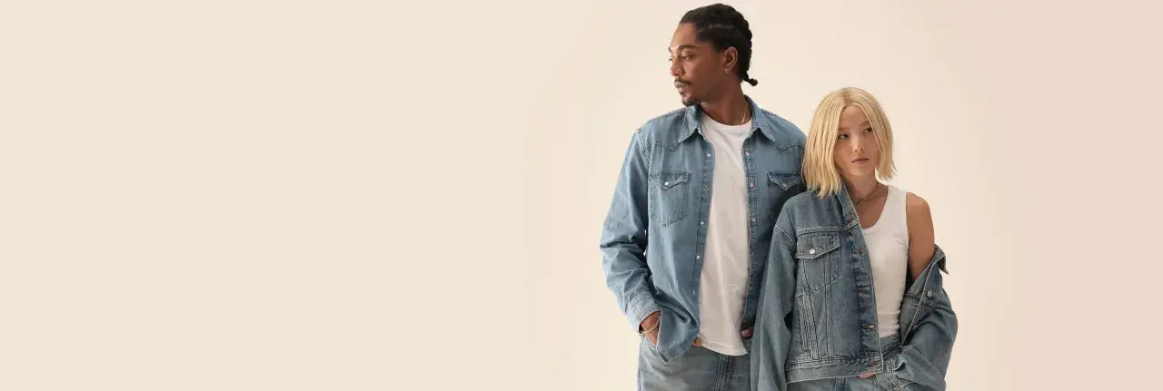 Två personer i jeanskläder, en man med flätor och en kvinna med blont hår, i en levis reklam.