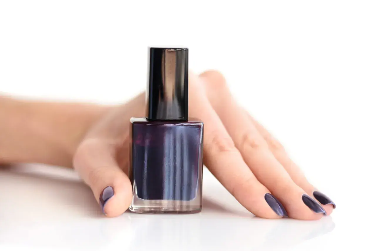 Mörkblått nagellack i en flaska, med en hand som visar matchande naglar. Perfekt för att torka nagellack snabbt.