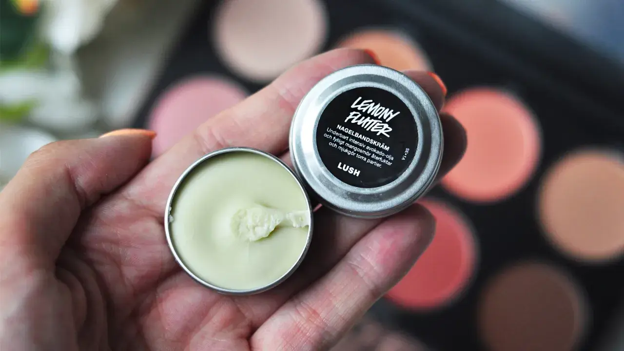 En hand håller en burk med Lemony Flutter nagelbands-kräm, perfekt för torra nagelband.