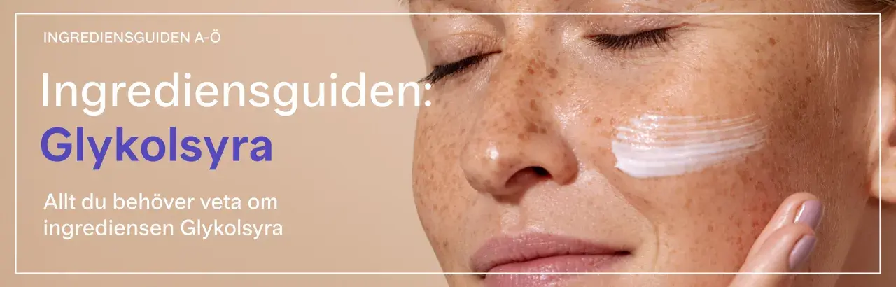 En närbild av en kvinna med fräknar som får en kräm med glykolsyra på kinden. Texten "Ingrediensguiden: Glykolsyra" syns tydligt.