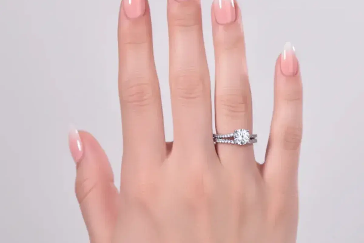 En hand med perfekt manikyr hemma visar upp en gnistrande diamantring och en matchande vigselring.