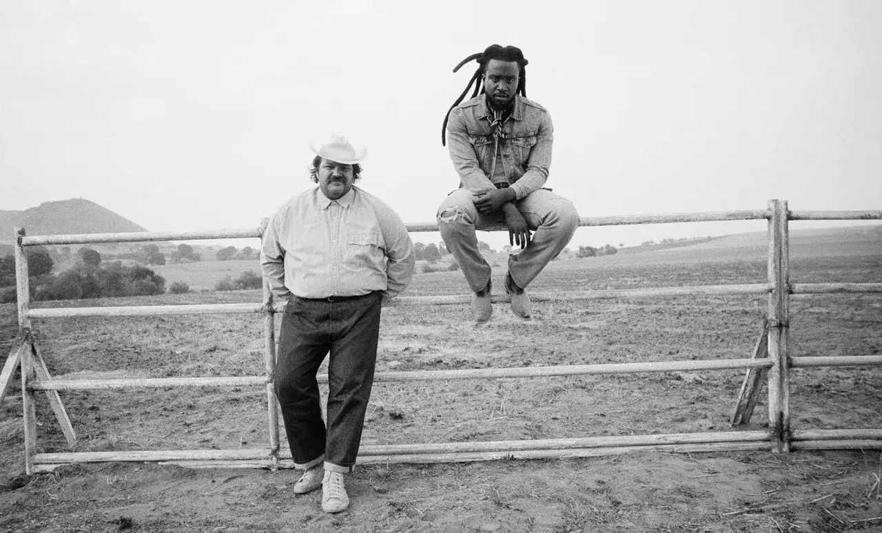 Två män i Levis reklam, en med cowboyhatt står vid ett staket, en annan med dreadlocks sitter på det.