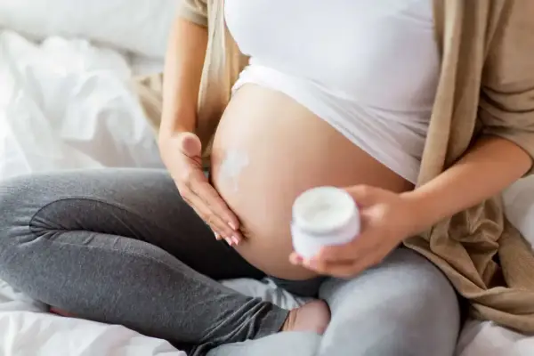 Gravid kvinna smörjer magen med kräm. Niacinamid kan vara bra för huden under graviditeten.